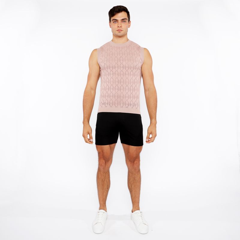 A man wearing a light pink sleeveless diamond pointelle knit vest with an intricate diamond pattern design