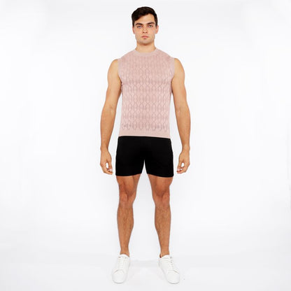 A man wearing a light pink sleeveless diamond pointelle knit vest with an intricate diamond pattern design