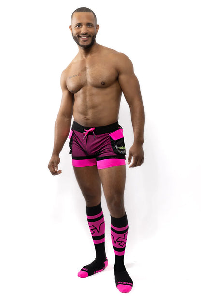 The man is wearing vibrant pink and black electro cargo shorts with a matching logo on the side