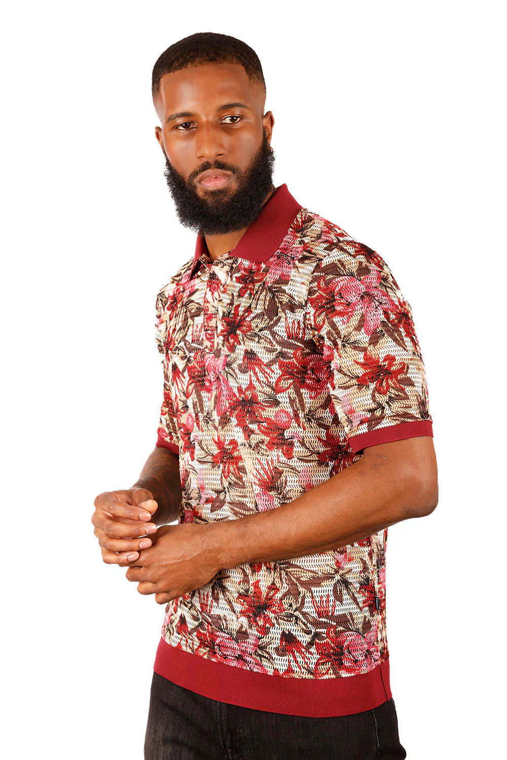 A man wearing an entwine form polo shirt with vibrant red pink and brown floral pattern and maroon accents on beige