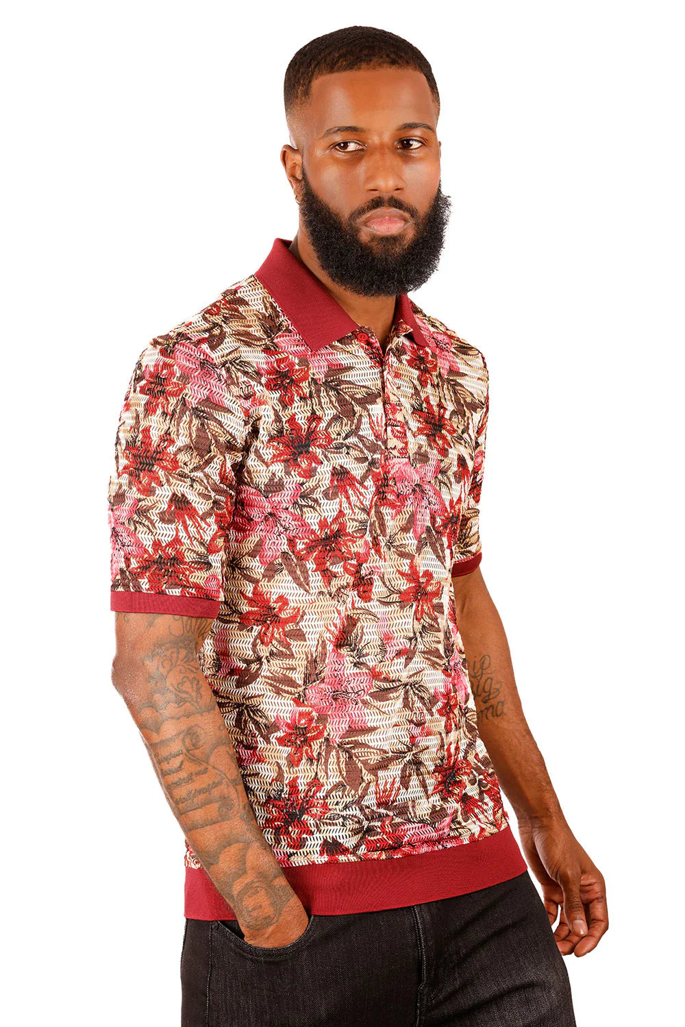 A man wearing an entwine form polo shirt with a vibrant red pink and brown floral pattern on beige fabric