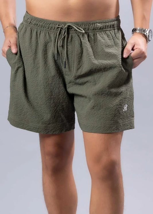 Olive green essential swim shorts with textured fabric drawstring waistband and embroidered logo on lower right leg