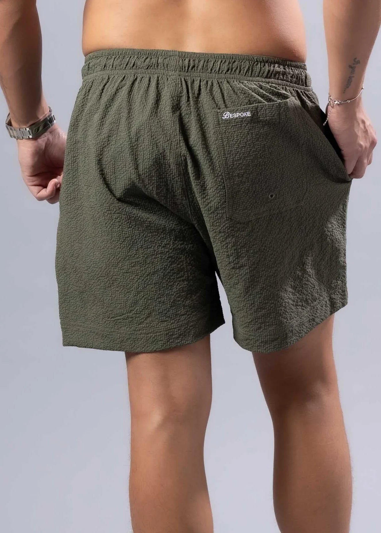 Back view of olive green essential swim short with textured fabric and branded logo on waistband available in 3 colors