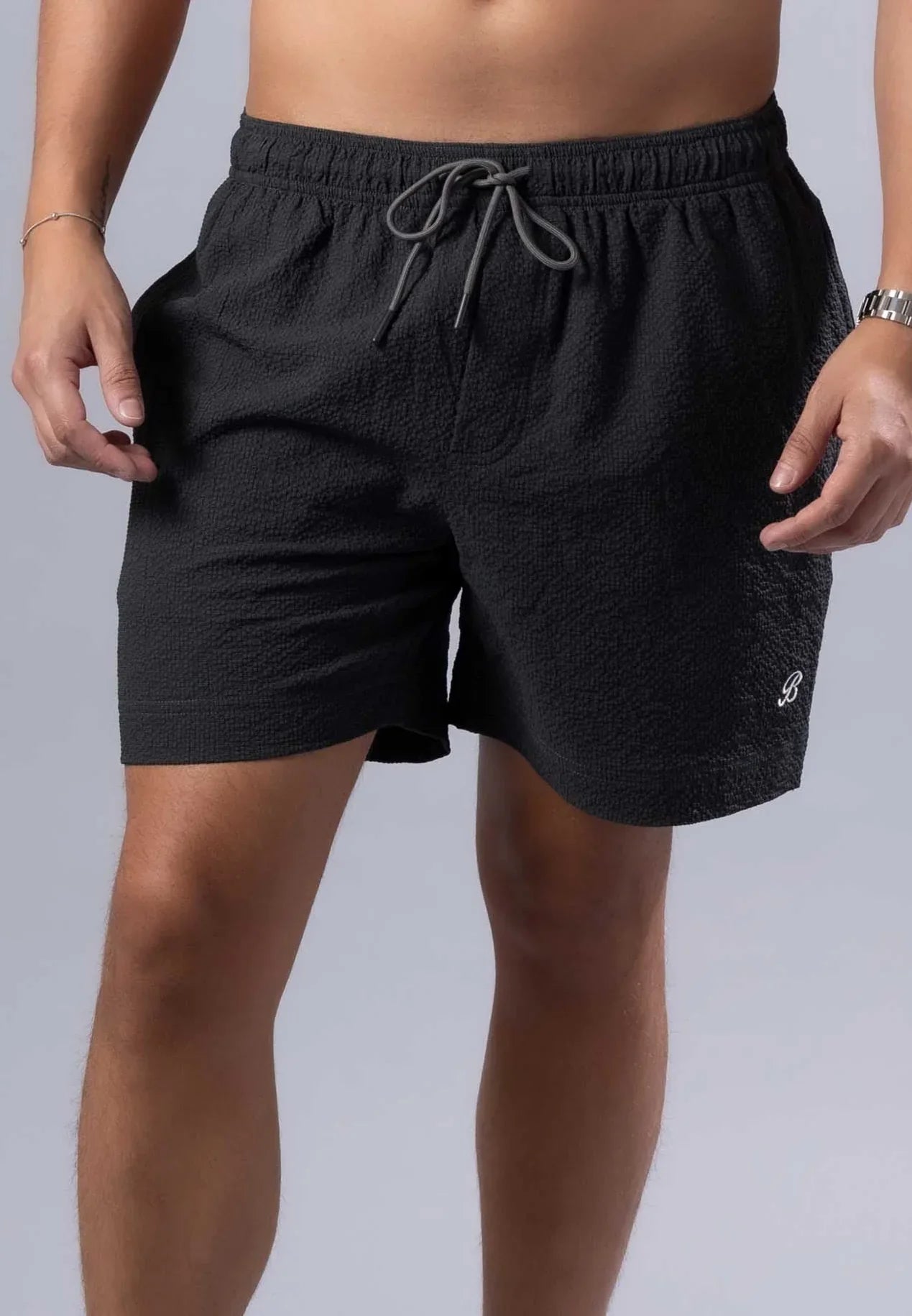 Black textured essential swim short with gray drawstring waistband and white logo on lower right leg available in 3 colors