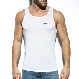 White basic tank top with a small black logo on the left chest, worn with blue jeans.