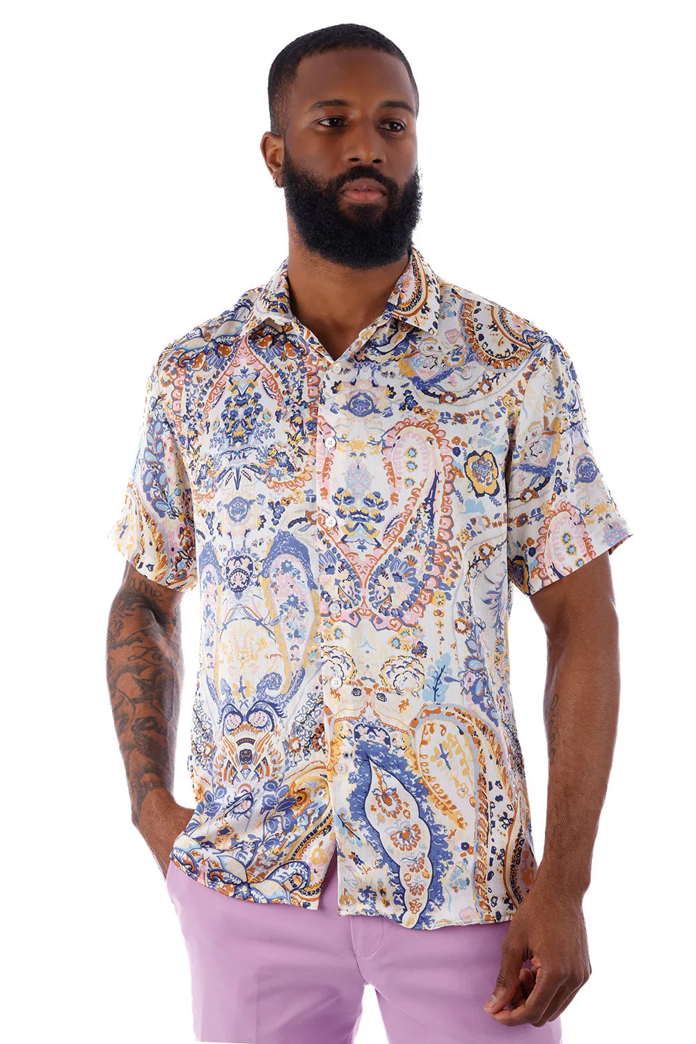 A man wearing an exclusive buzz s s shirt with an intricate blue orange and cream paisley pattern on a light background
