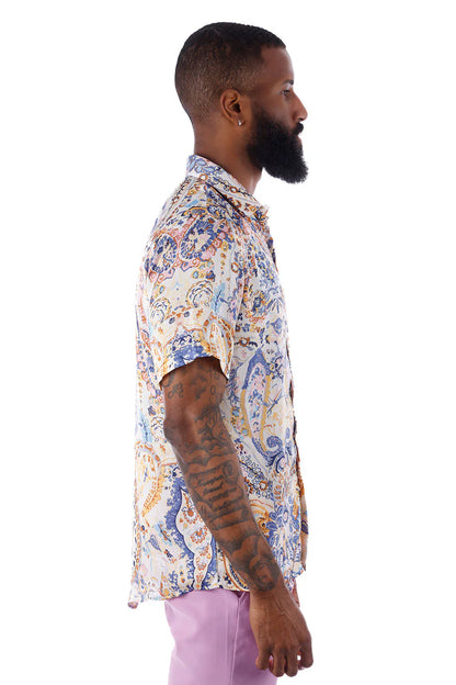 A man wearing an exclusive BUZZ short-sleeved shirt with blue orange and cream paisley pattern on light fabric