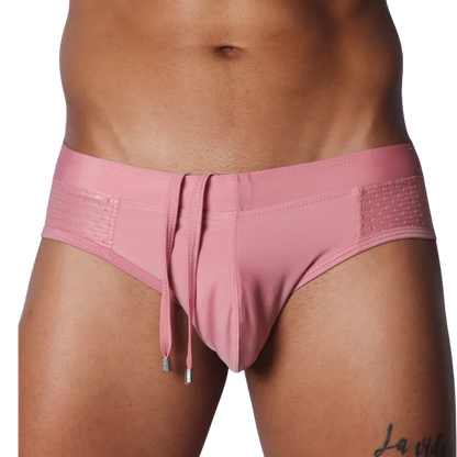 Dusty pink swim brief with a smooth center, side mesh panels, and hanging decorative drawstrings with silver tips.