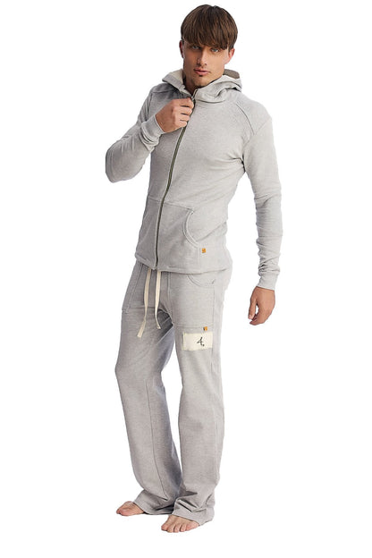 A man wearing heather grey edge eco-track and yoga sweatpants with side pockets and a matching light gray zip hoodie