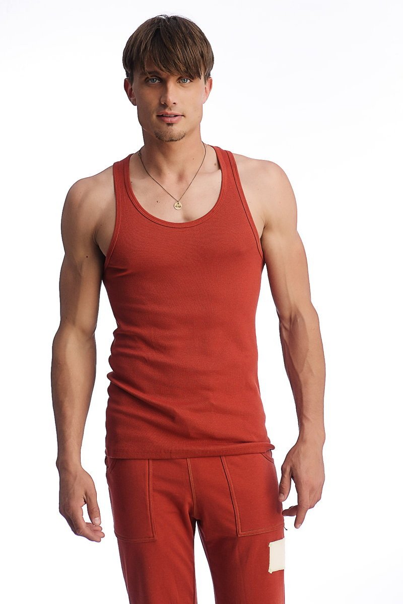 A man wearing an edge sustain tank top cinnabar in ribbed fabric with a scoop neckline and matching red pants