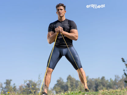 A man wearing ergoWear ew1607 max se dark blue athletic compression shorts holding yellow resistance bands