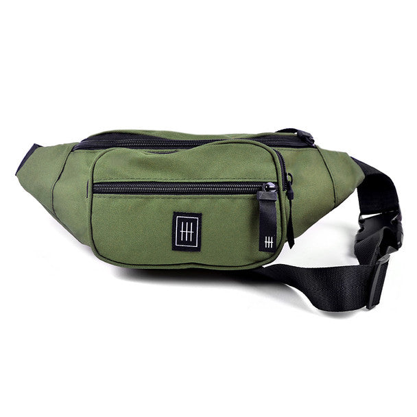 Olive green canvas fanny pack with black zippers and minimalist logo patch for hands-free carrying