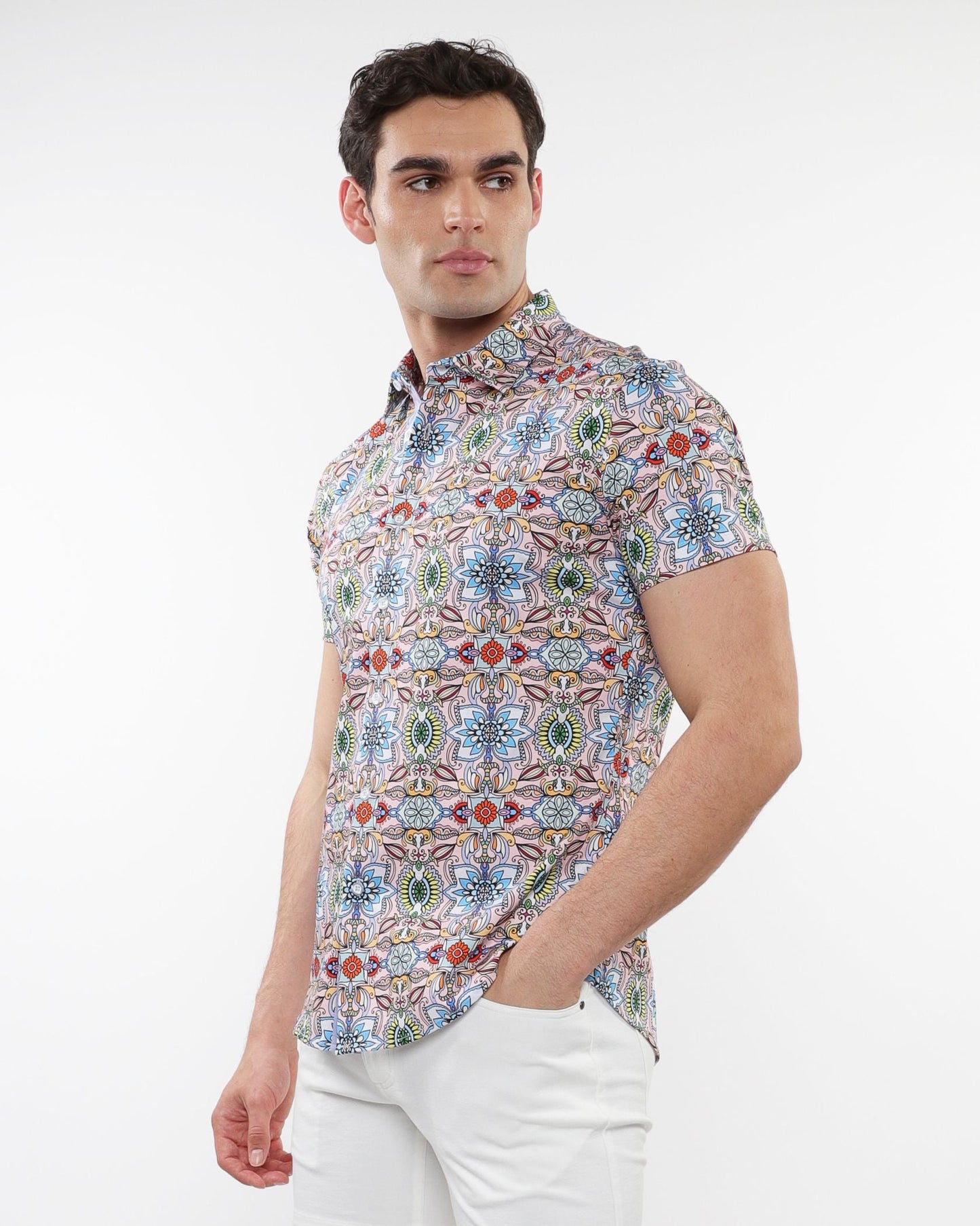 A man wearing a fauna print stretch knit short-sleeved shirt with colorful geometric and floral pattern on light background