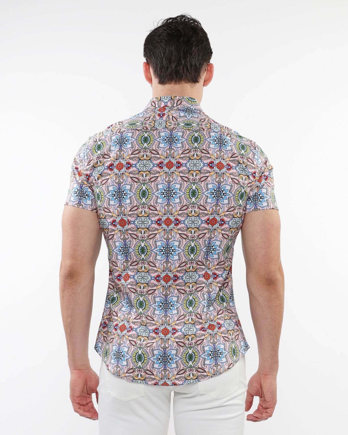 A man wearing a fauna print stretch knit short-sleeved shirt with colorful geometric and floral patterns on light fabric