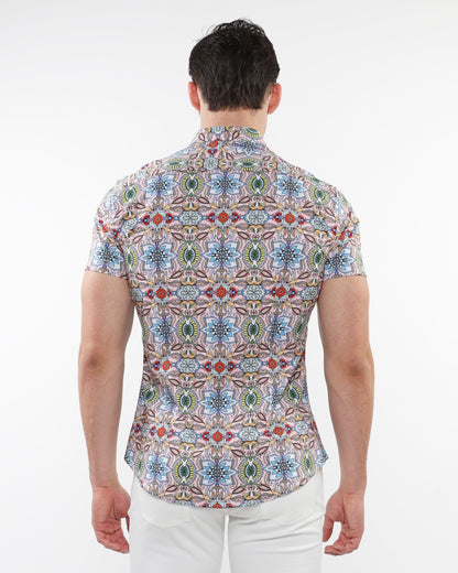 A man wearing a fauna print stretch knit short-sleeved shirt with colorful geometric and floral patterns on light fabric