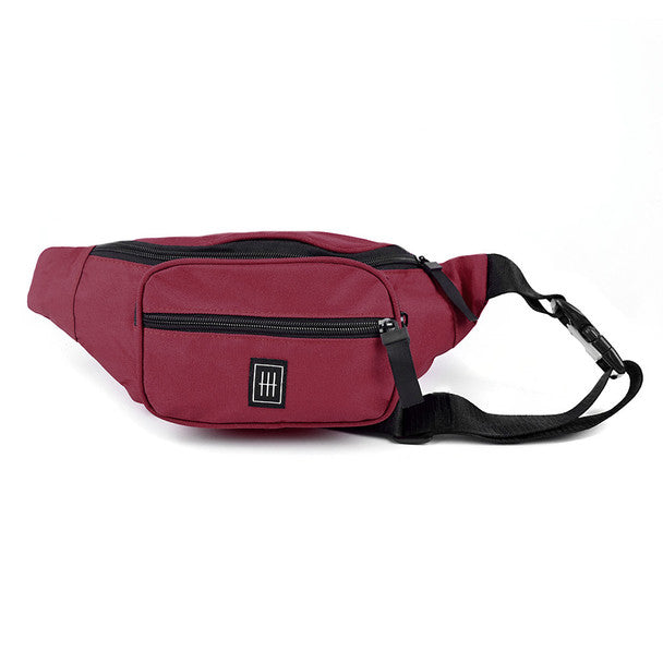 Maroon fanny pack with a black zipper, front pocket, square logo, and black strap.