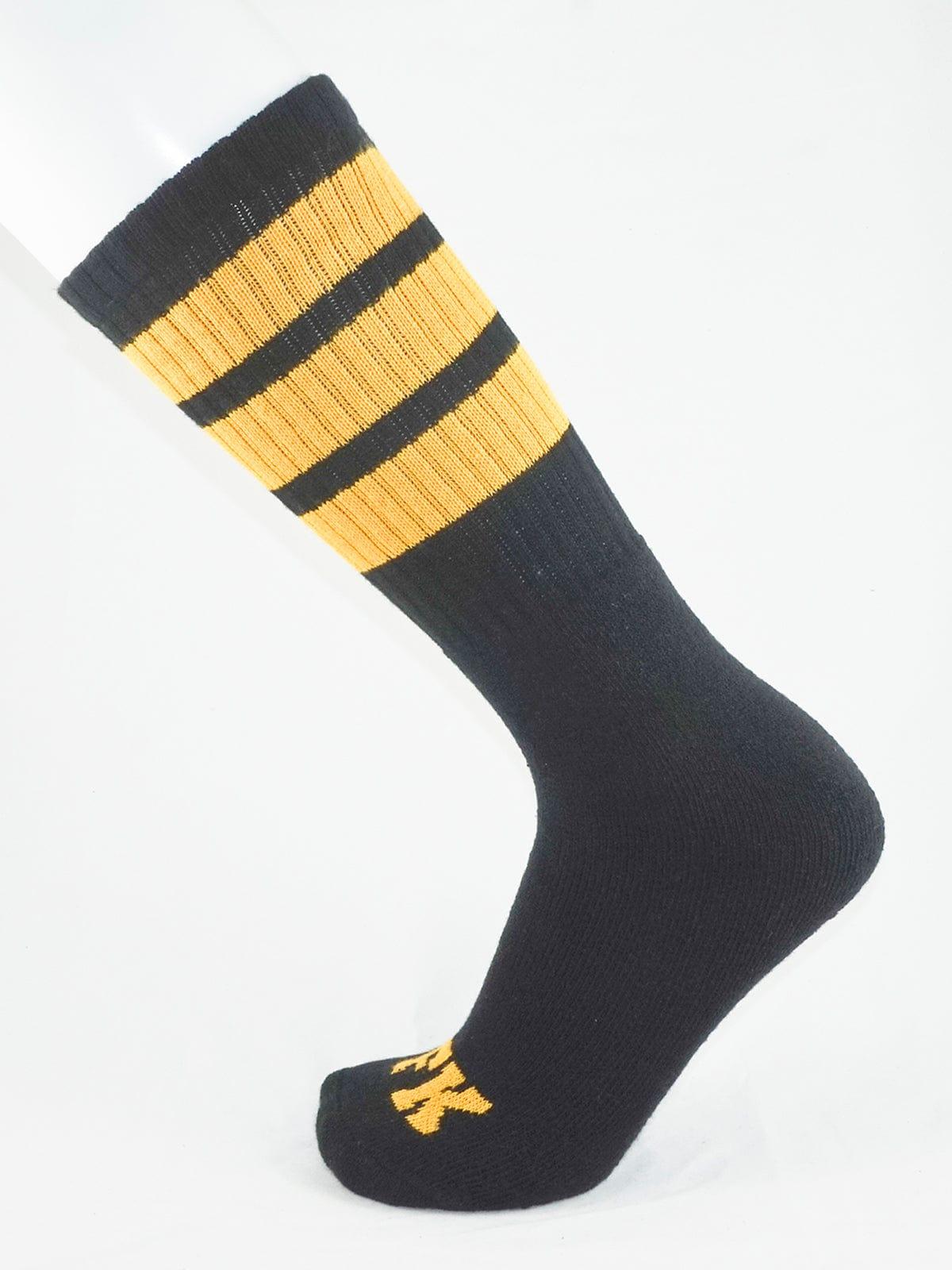 Fk sport black tube sock with three gold stripes near the top and a small gold logo on the toe made for athletic use