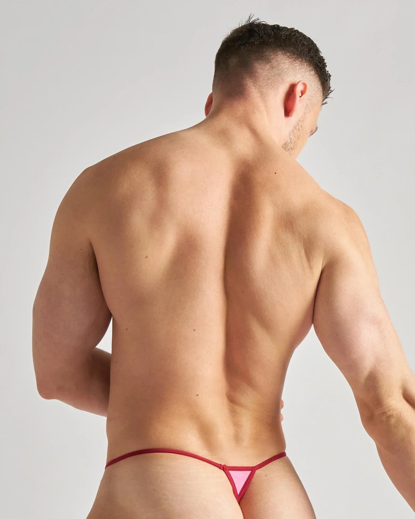 Pink triangular micro thong with red trim featuring sheer mesh fabric for a bold and flirty look