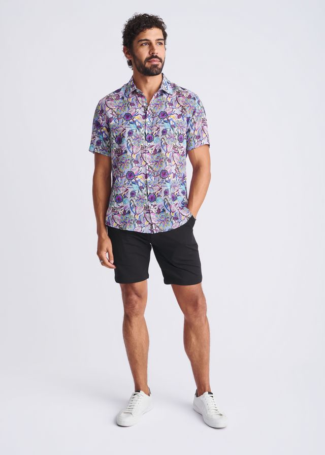 A man wearing a floral lightweight linen tencel short-sleeved shirt in shades of purple blue and pink