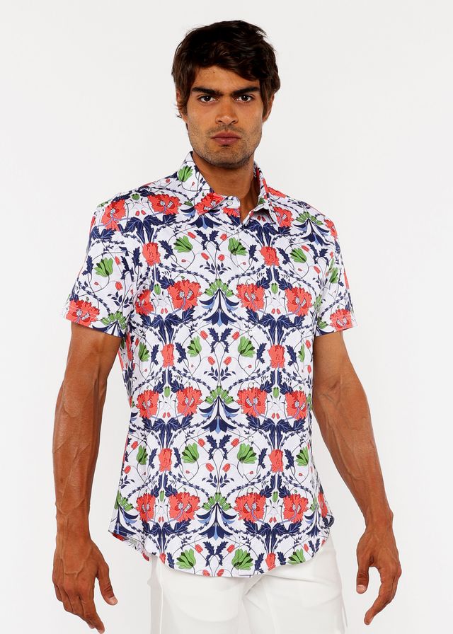 A man wearing a white floral print stretch knit shirt with red poppies green leaves and navy blue accents