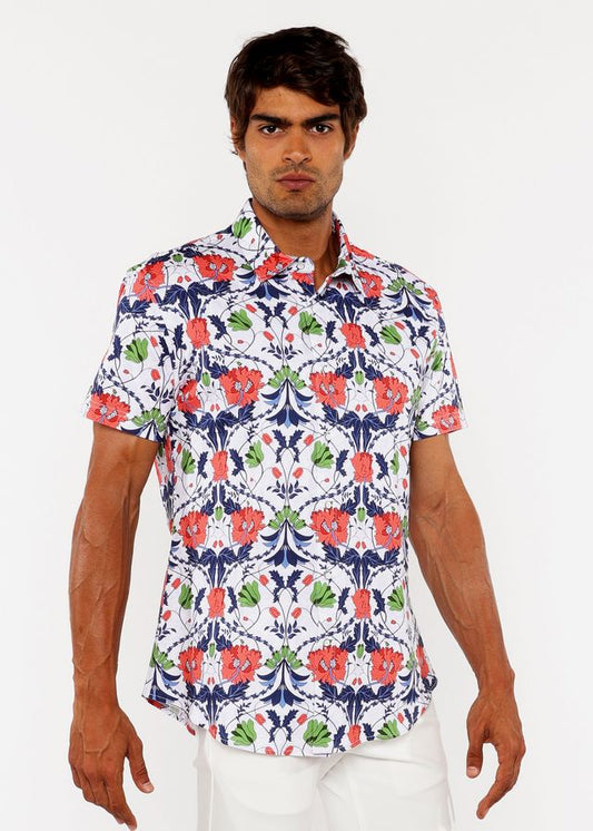 A man wearing a white floral print stretch knit shirt with red poppies green leaves and navy blue accents