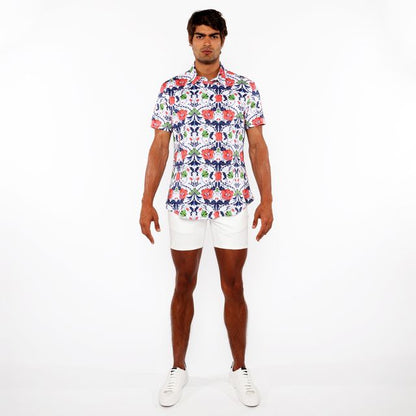 A man wearing a floral print stretch knit shirt with red blue and green flowers on white short-sleeved button-up shirt
