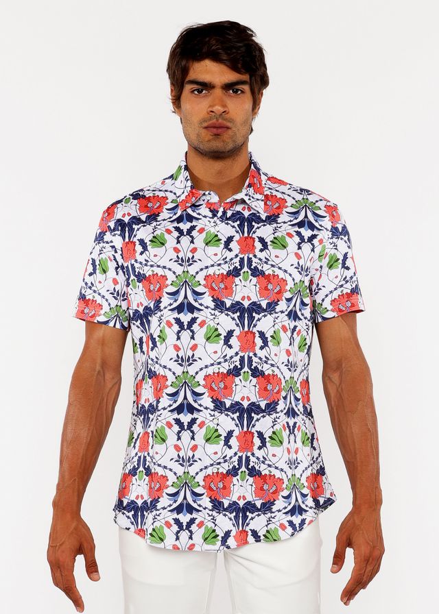 A man wearing a white floral print stretch knit shirt with red poppies green leaves and navy blue vines