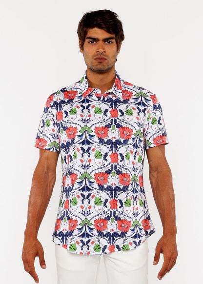 A man wearing a white floral print stretch knit shirt with red poppies green leaves and navy blue vines