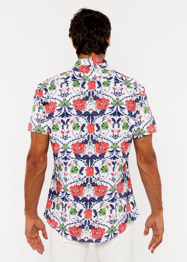 A man wearing a white floral print stretch knit shirt with red poppies and green leaves on navy blue vines