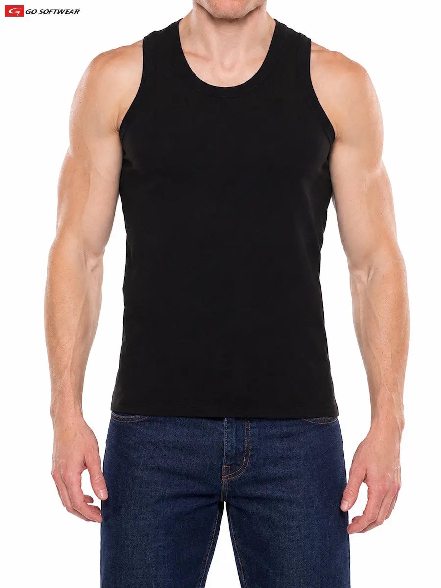A muscular man wearing a black tank top from Go Softwear paired with blue jeans standing against a plain background
