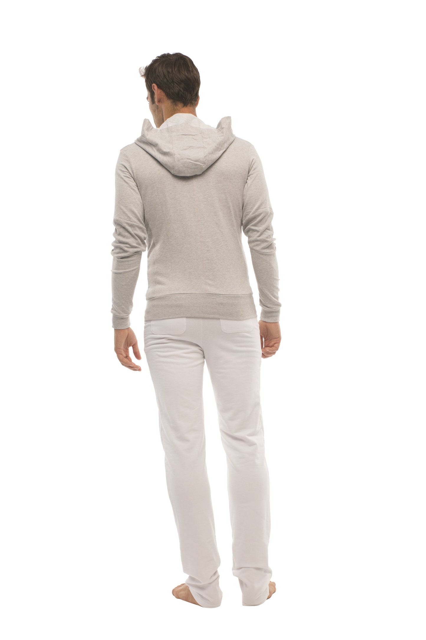 A man wearing a heather gray form-fit crossover yoga track performance hoodie with ribbed cuffs and waistband paired with white pants