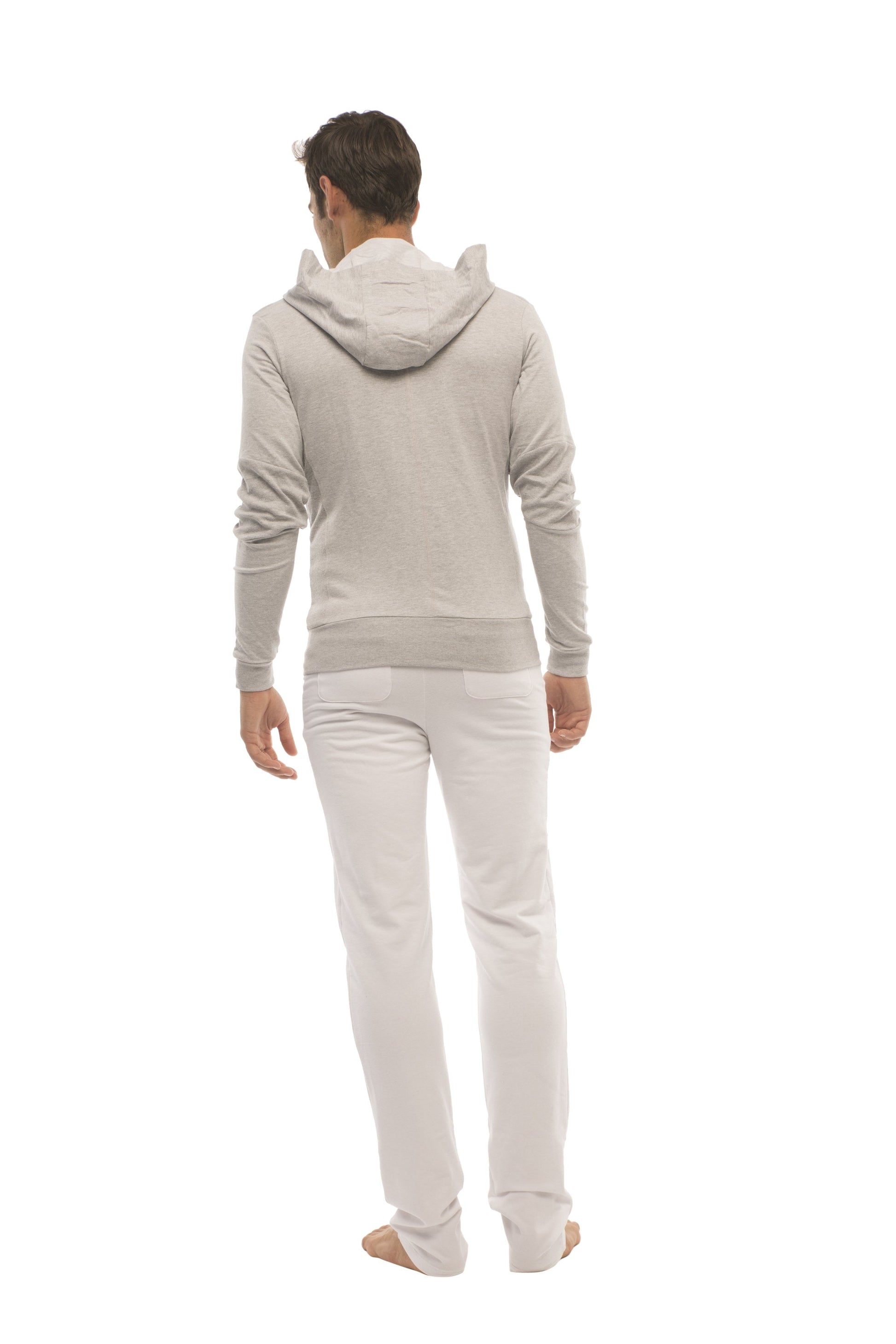 A man wearing a heather gray form-fit crossover yoga track performance hoodie with ribbed cuffs and waistband paired with white pants