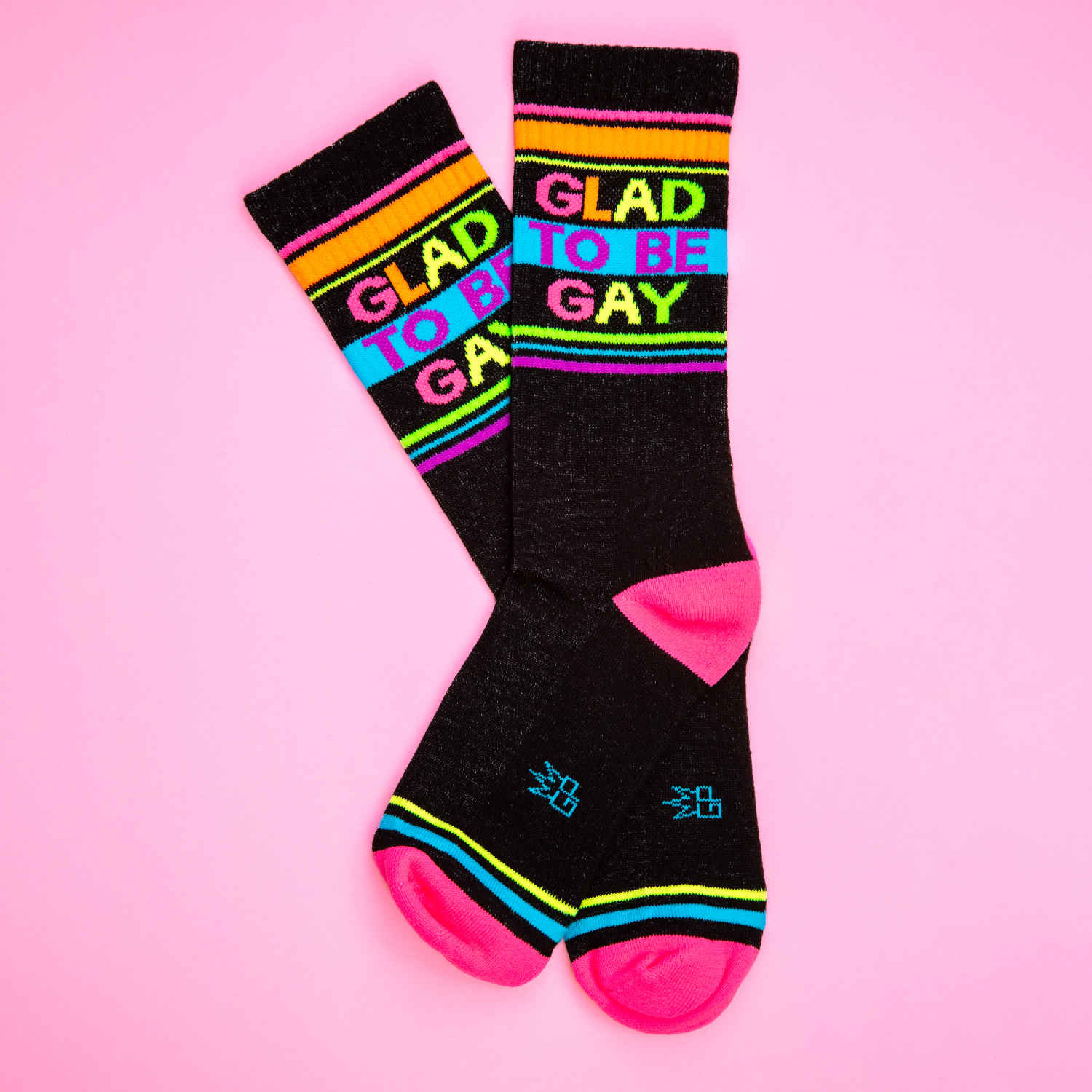 Black crew socks with vibrant rainbow stripes and glad to be gay in bold colorful letters across the top