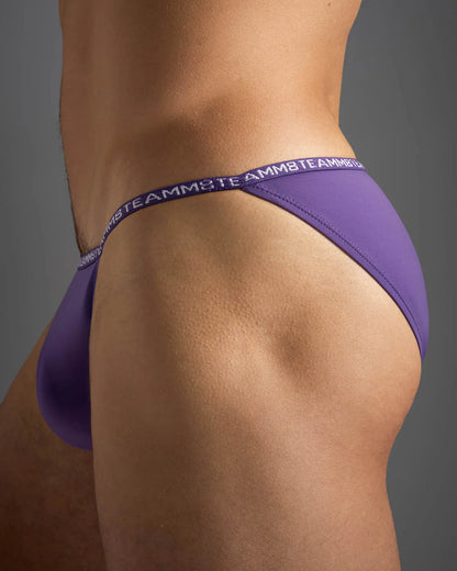 Purple glide micro brief thong with matching waistband featuring teamb logo in white lettering backside view