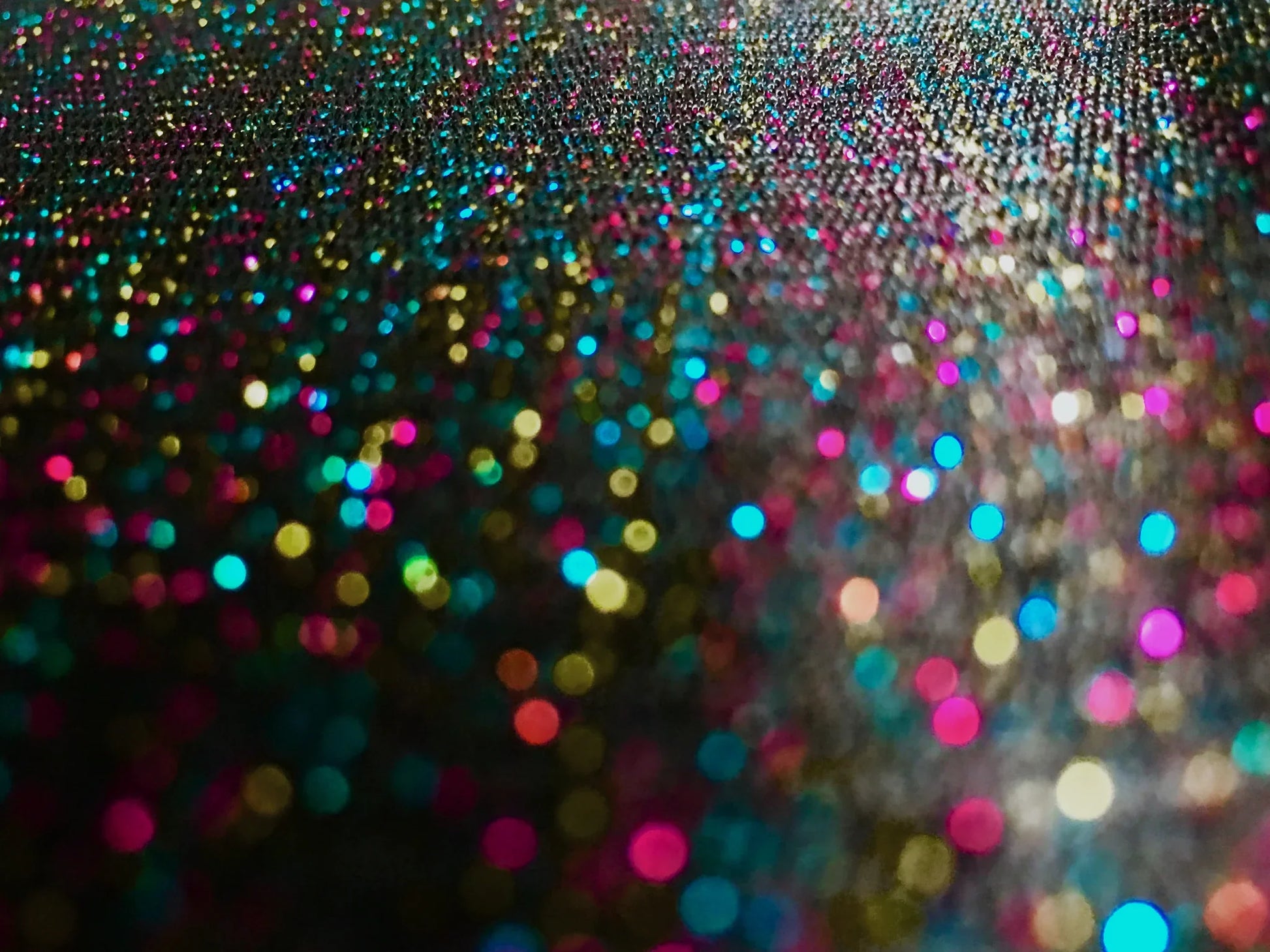 A glitter mesh tank featuring a vibrant multicolored glitter surface with pink blue gold and teal shimmering particles