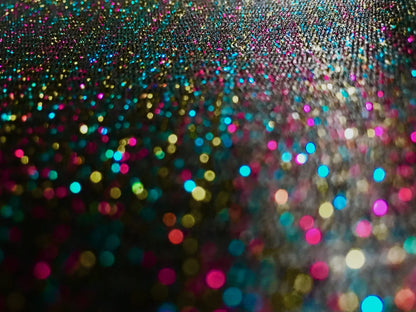 A glitter mesh tank featuring a vibrant multicolored glitter surface with pink blue gold and teal shimmering particles
