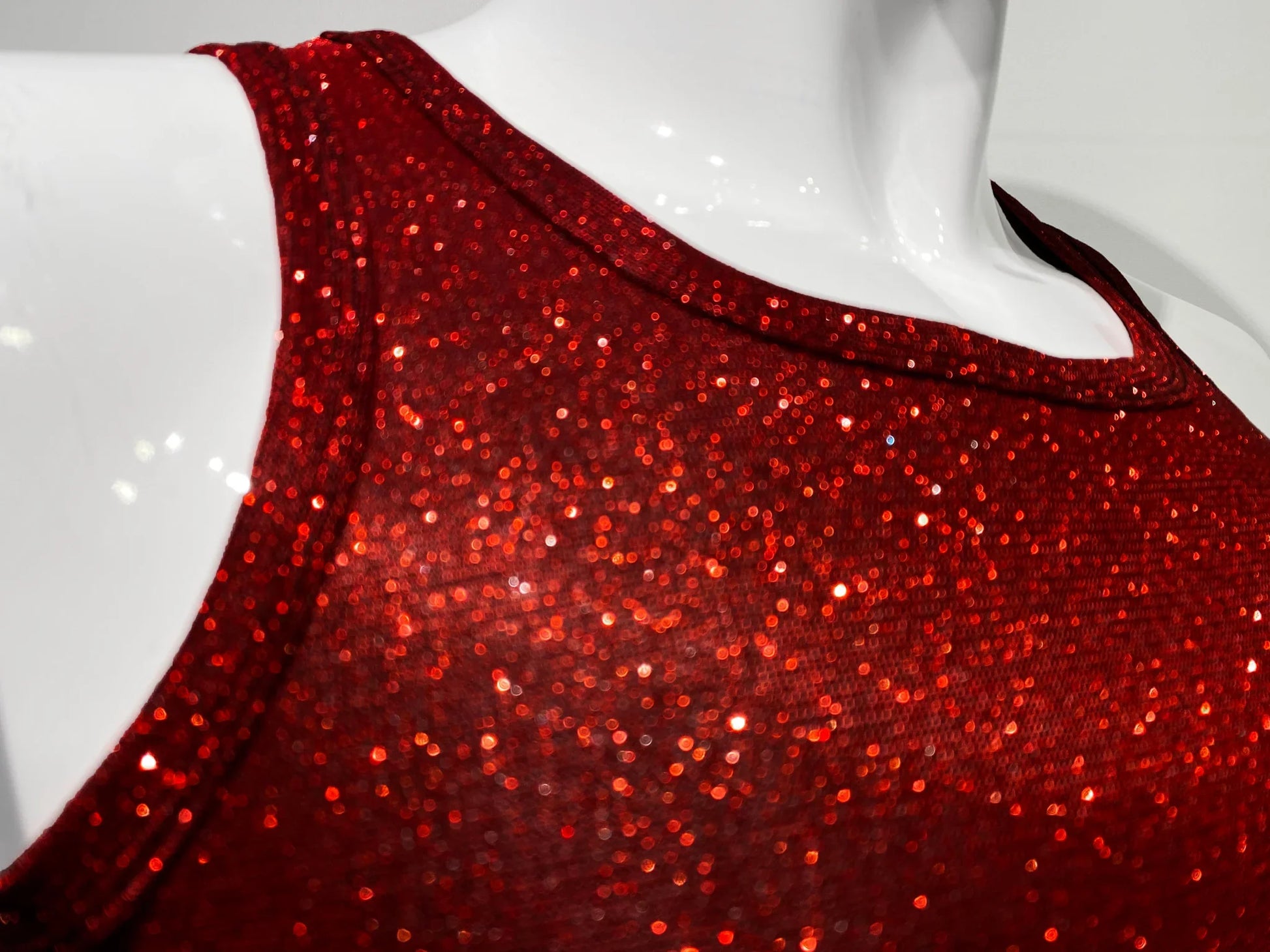 A vibrant red sequined sleeveless glitter tank top with a shimmering glittery texture for festive wear
