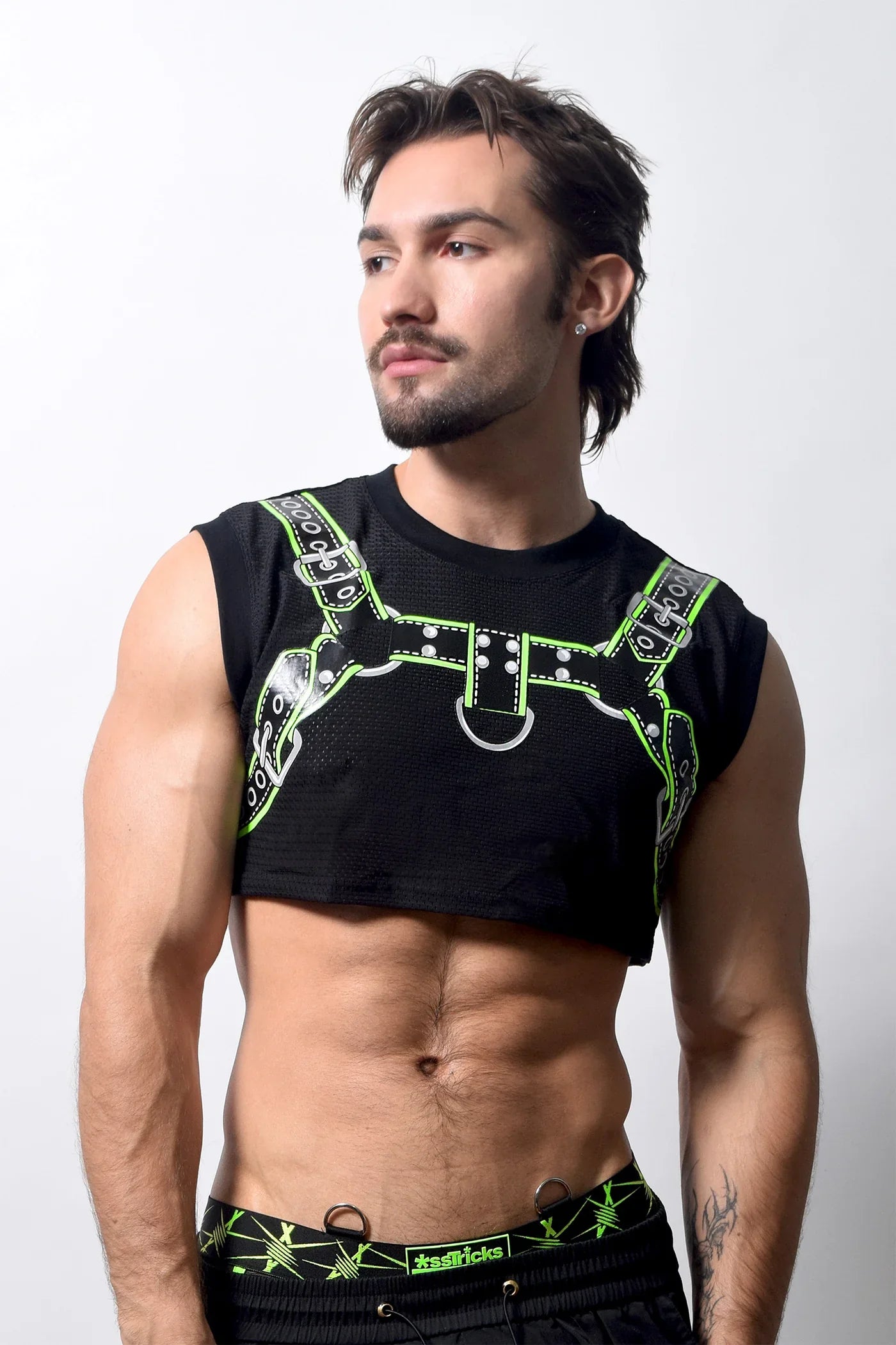 Black harness crop top with neon green leather-like straps and silver hardware highlighting sleeveless design