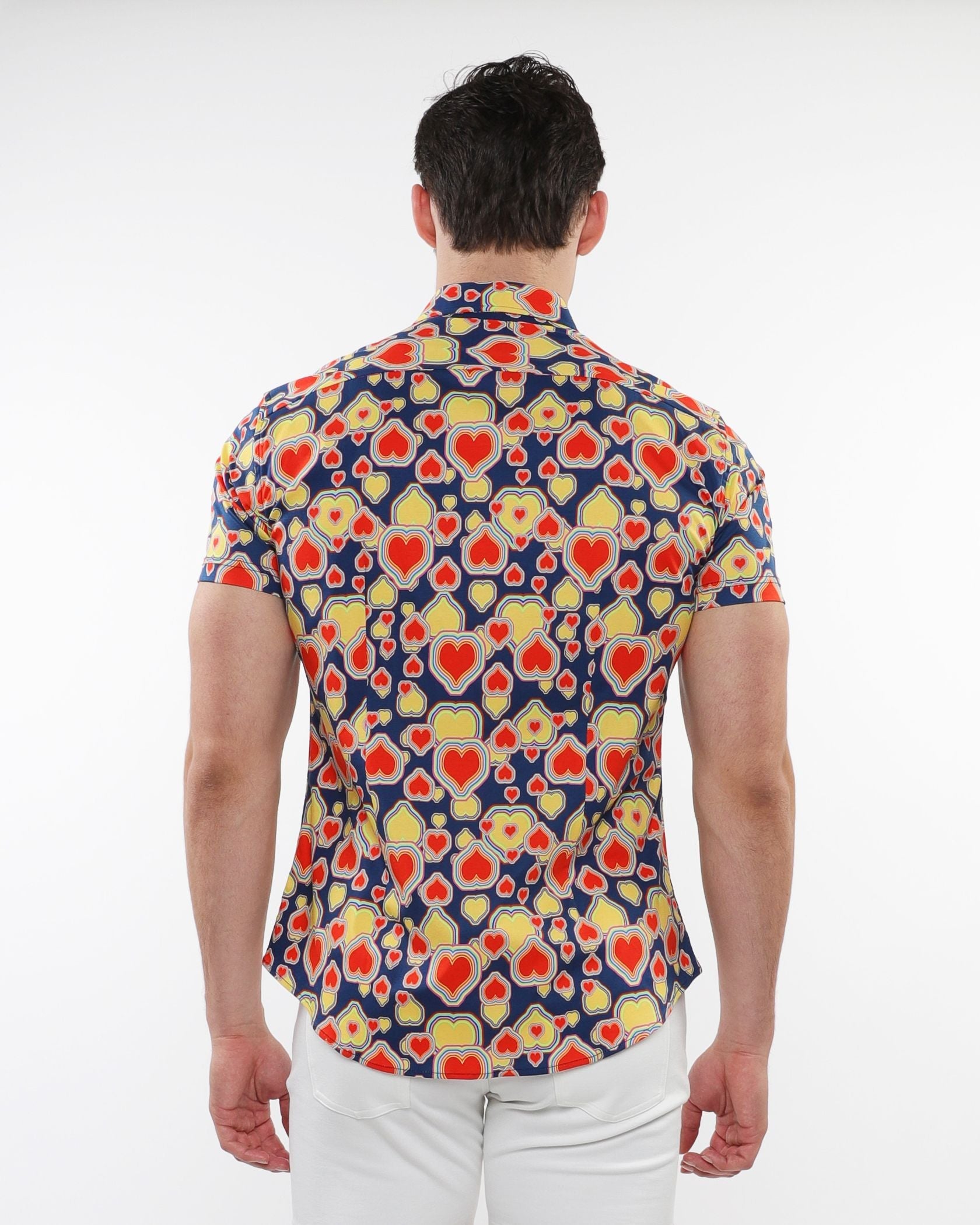 A man wearing a navy blue hearts print stretch knit short-sleeved shirt with red and yellow heart patterns