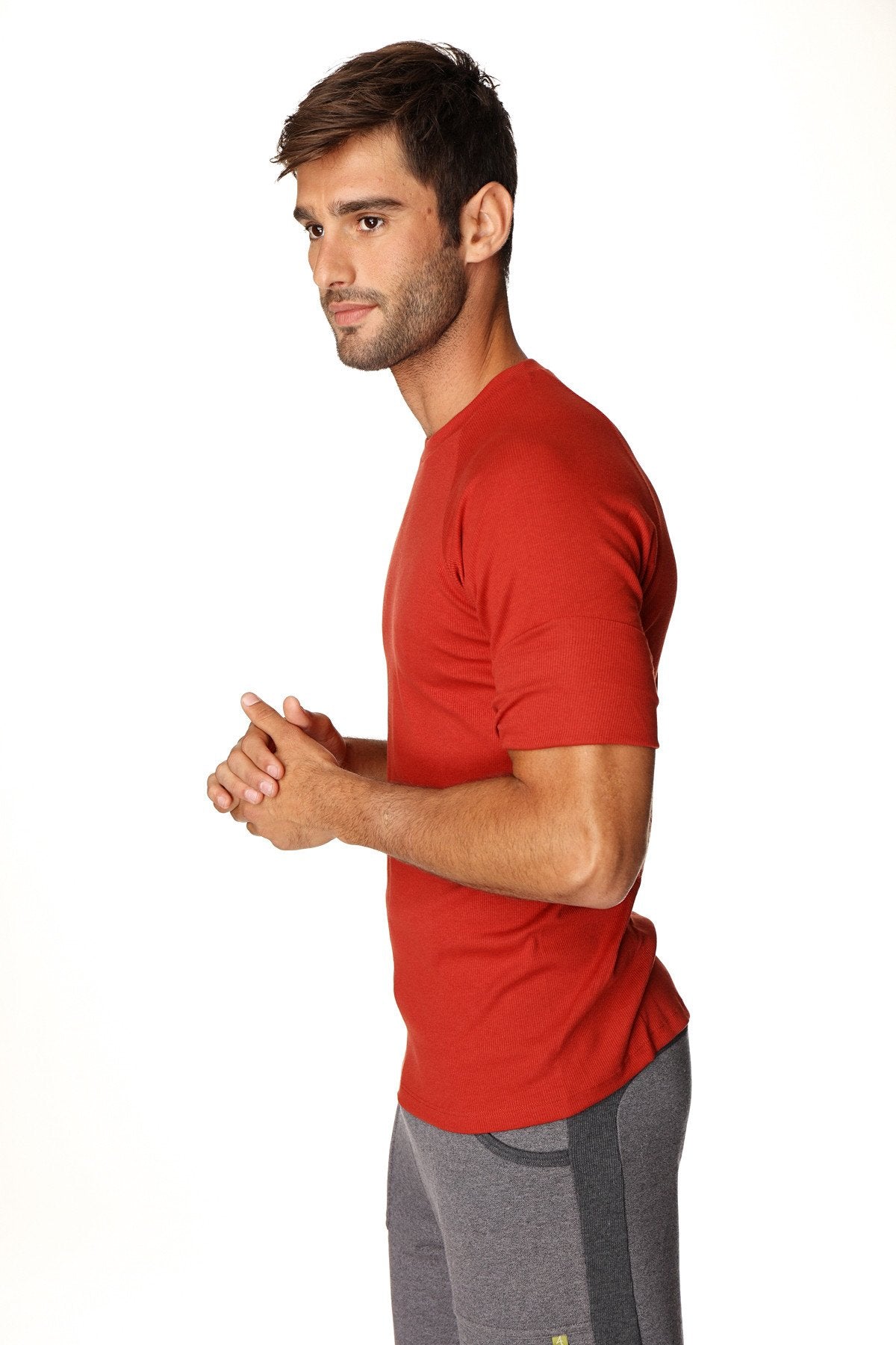 A man wearing a cinnabar red hybrid crew neck raglan athletic tee with short sleeves made for active use