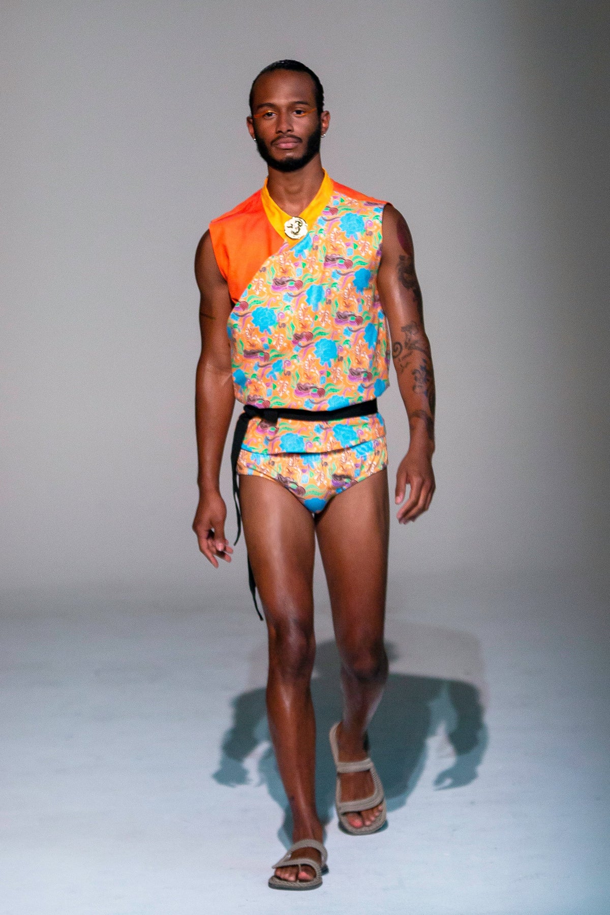 Model wearing a colorful batik print outfit with a sleeveless top and fitted shorts by Maris Equi paired with sandals.