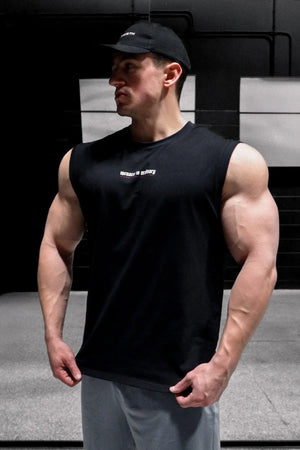 Muscular man wearing a black sleeveless muscle tee from Jed North showcasing strong arms in a gym setting
