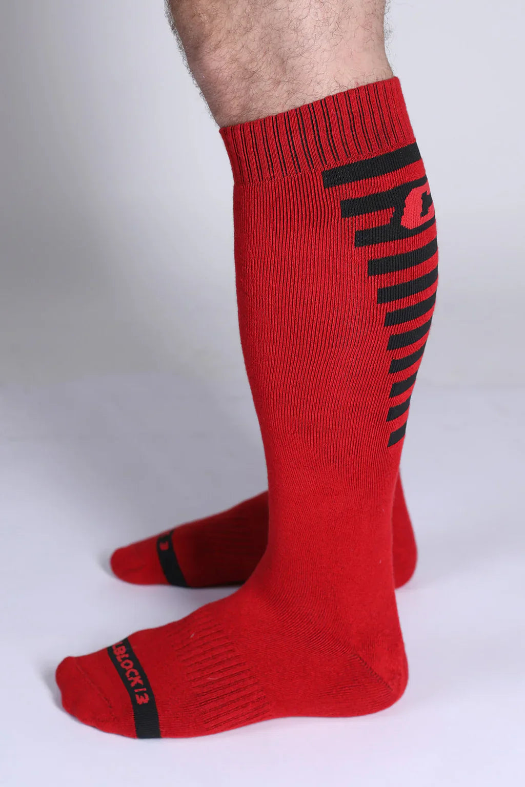 Iron grip knee high sock in red with black horizontal stripes and logo on the side made from durable material