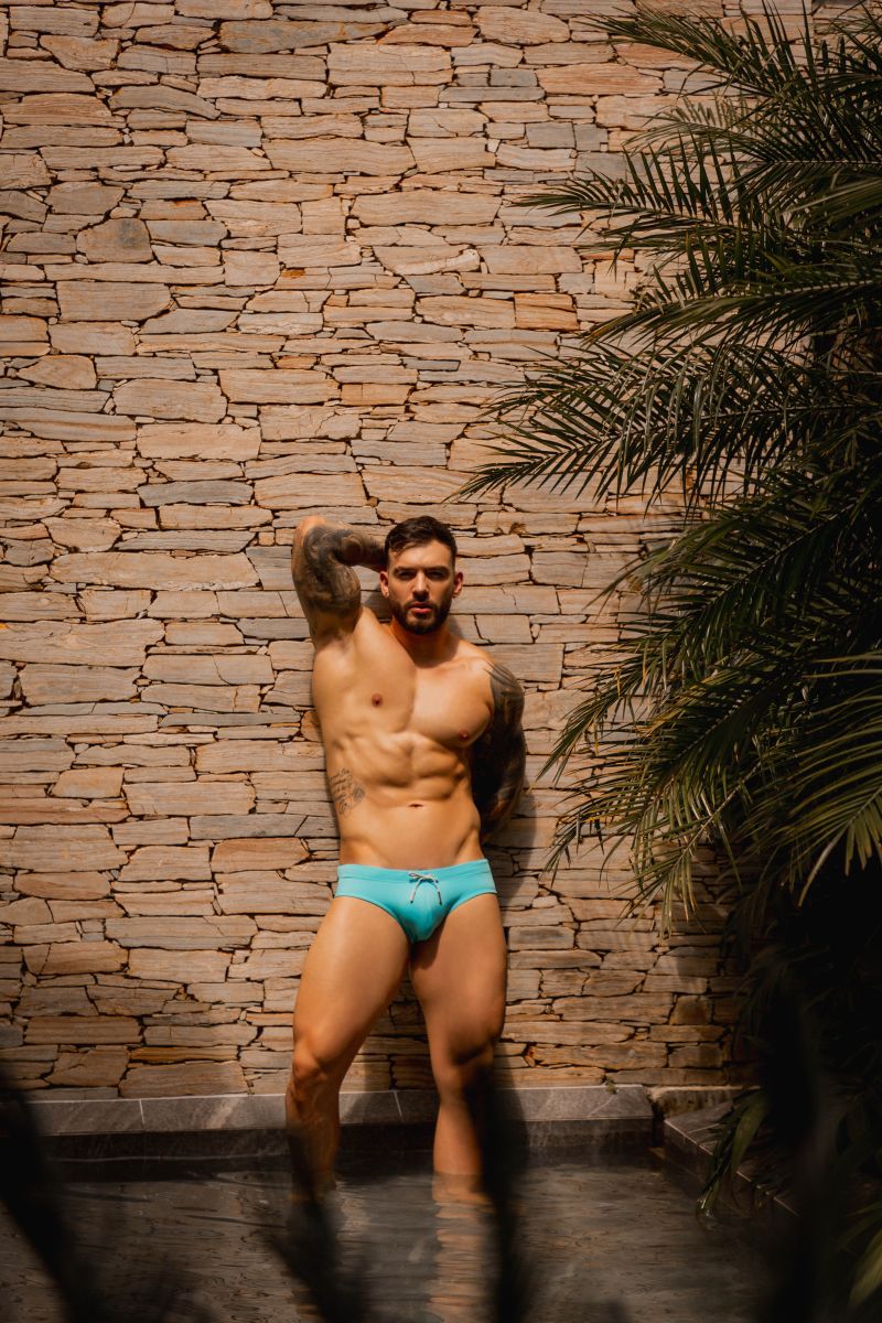 A man wearing jor 2387 travel swim briefs in bright turquoise with a simple drawstring waistband
