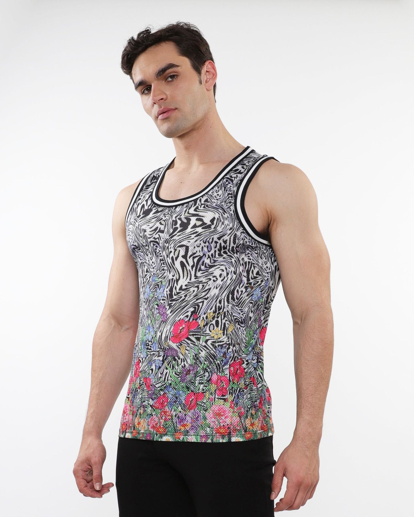 A men’s jungle printed mesh tank with stripe ribbing features black and white swirls and vibrant floral patterns near the hem