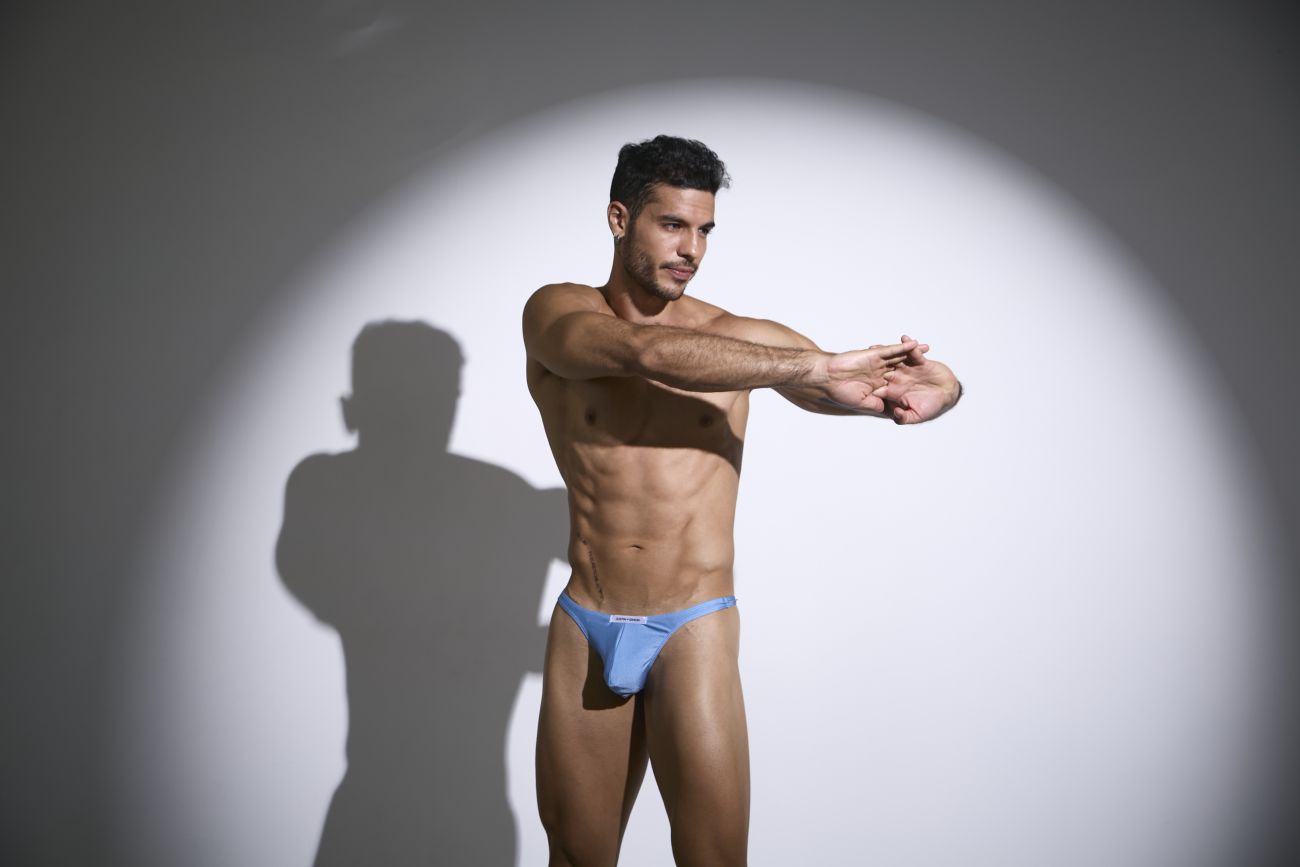A man wearing justin simon xsj03 classic baby blue briefs with a small white logo on the front in a form-fitting style