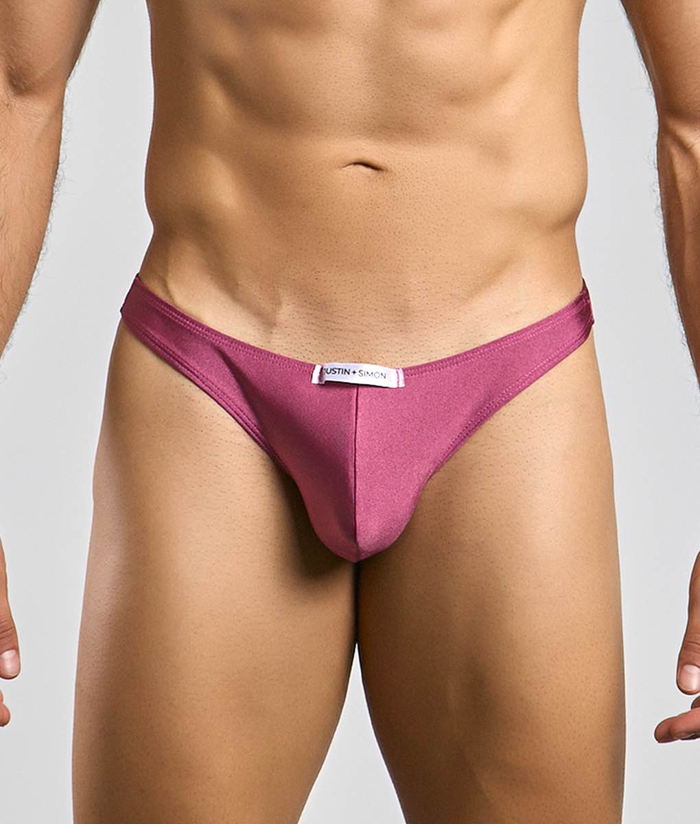 A sleek magenta Justin + Simon classic tanga thong made of smooth fabric with a minimalist design and white waistband label