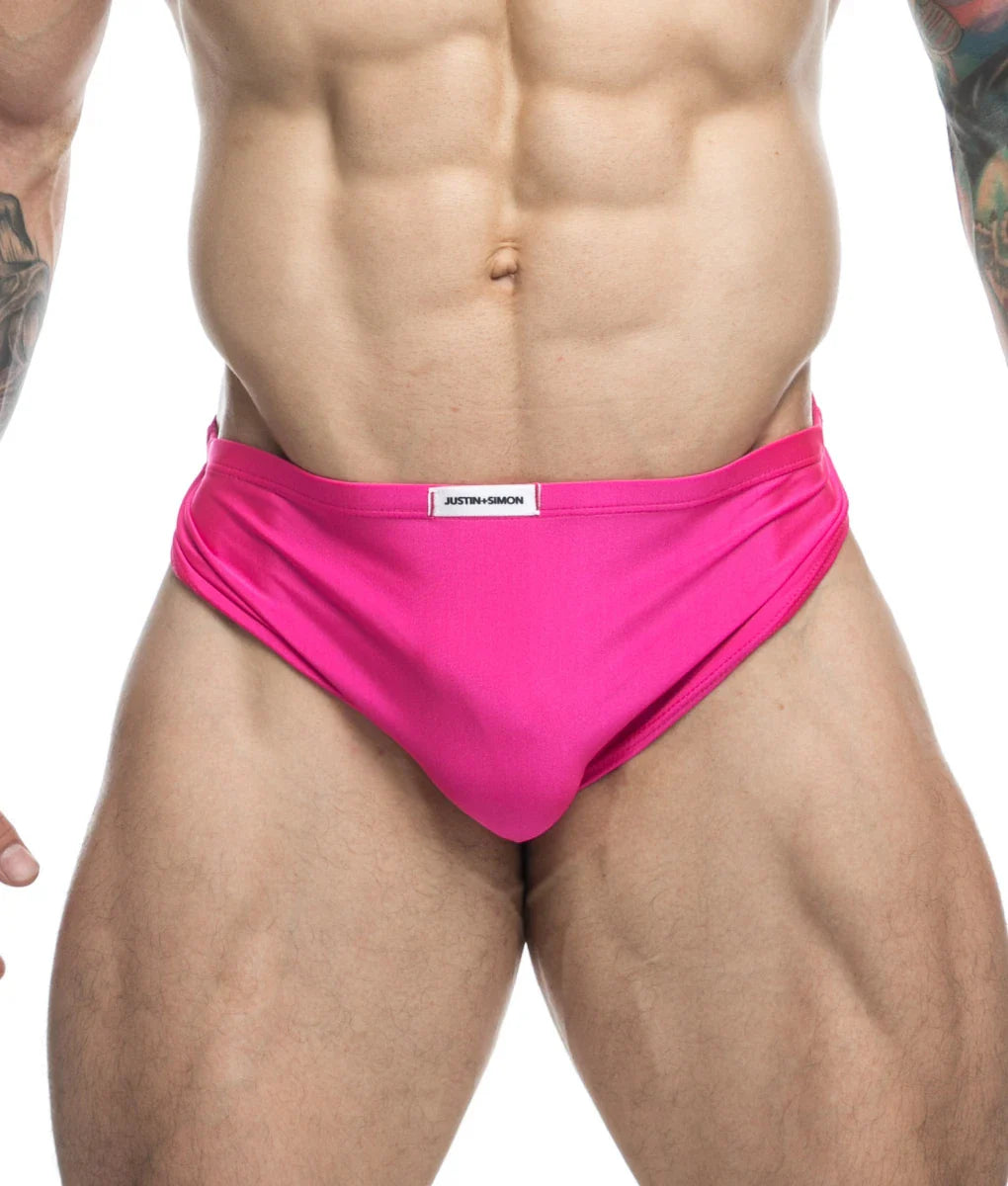 Bright pink justin simon running shorts with smooth form fitting fabric and white brand label at the waistband