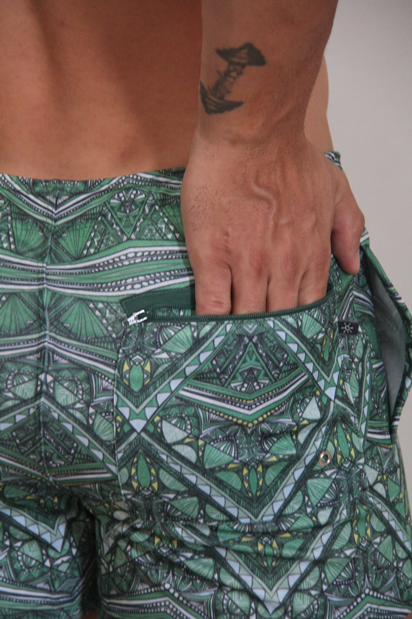Kaleidoscope shorts green patterned swim trunks with geometric and tribal designs in shades of green black white and yellow