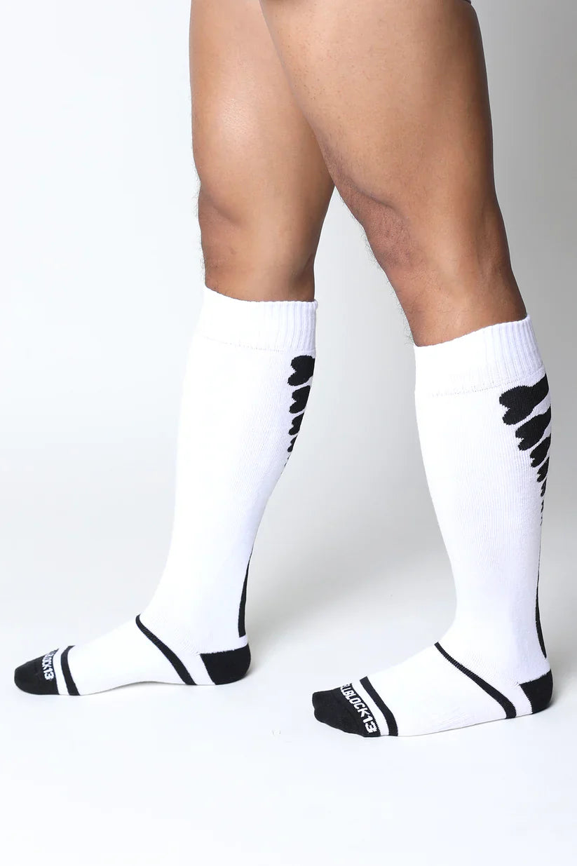 White kennel club bones knee high athletic socks with black wing patterns and branding on the heel back view